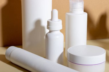 Yüz ve vücut bakımı için kadın profesyonel kozmetik seti. Bej arka planda cilt bakımı ürünü ve sert gölgeli kozmetik tüp.