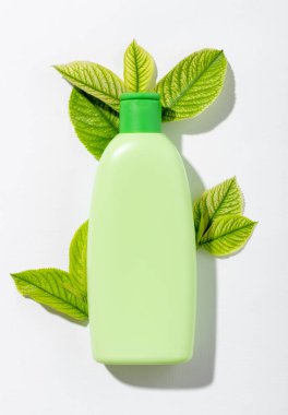 Kozmetik ürünü yeşil tüpte markalaştırmak için boş alan var. Cilt ve saç bakımı için doğal kozmetik ürünleri. Beyaz arka planda yaprak gölgesi olan şampuan ya da losyon