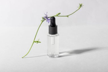 Beyaz arka planda nemlendiricisi olan şeffaf cam bir şişe.