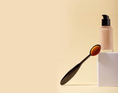 Bir şişe sıvı fondöten ve makyaj fırçası standda..