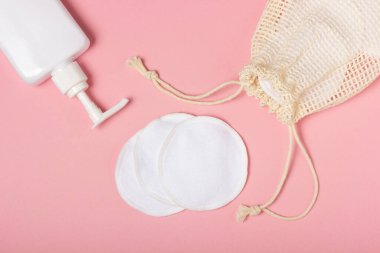 Pamuk çıkarılabilir makyaj pedleri bir bez torba içinde ve yüz yıkama ve pembe arka planda temizleyici. Ekoloji ve bilinçli tüketim kavramı. Yeniden kullanılabilir pamuk pedleri