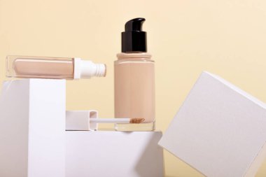 Sehpada bir şişenin içinde sıvı bazlı ve geometrik şekillerin arka planına karşı gizleyici. Bej arkaplanda kopya alanı olan yüz düzeltici. Kopyalama alanı olan paketleme modeli