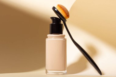 Bir şişe sıvı fondöten ve makyaj fırçası standda..