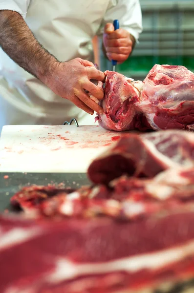 Carnicero cortando carne cruda en una carnicería — Foto de Stock
