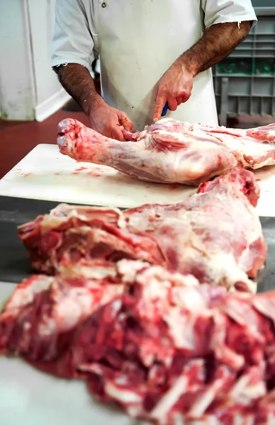 Carnicero cortando sangrientos cuartos traseros — Foto de Stock