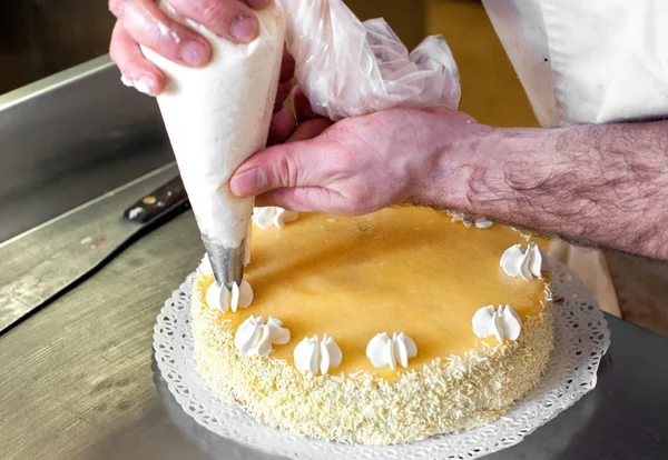 Baker decoración de la crema de tuberías en un pastel — Foto de Stock