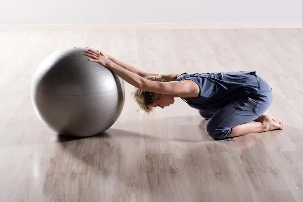 Mulher esticando ombros com bola de fitness — Fotografia de Stock