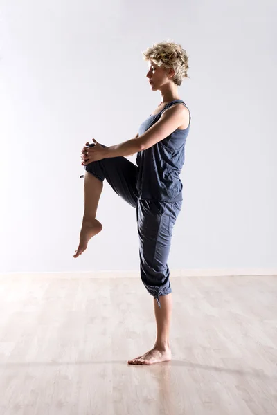Ισορροπημένη γυναίκα κρατώντας το γόνατο ψηλά — Φωτογραφία Αρχείου