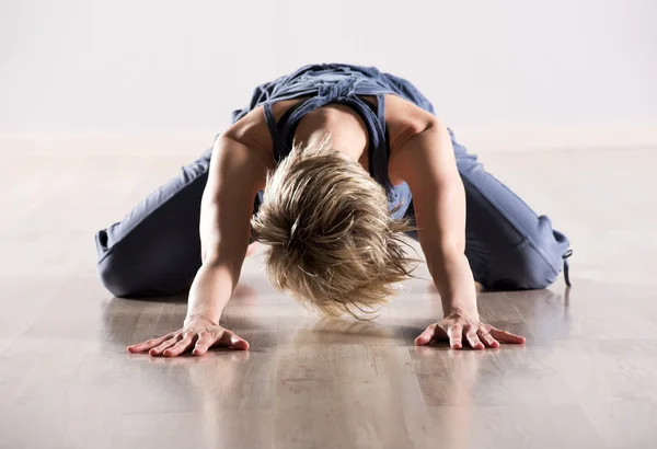 Woman with head down while stretching hip muscles Stock Picture