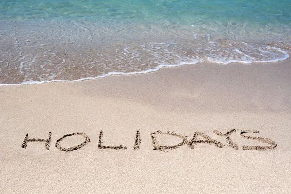 Word Holidays dibujado en una playa tropical —  Fotos de Stock