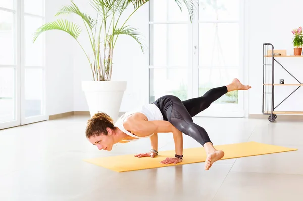 Koundinyasana瑜伽姿势或飞碟式的手臂平衡姿势由一名女子在一个高度关键的健身房里进行 旁边有一个健康和健康的运动空间 — 图库照片