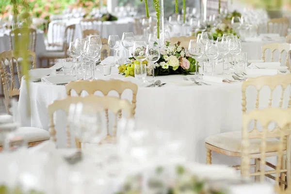 スタイリッシュな白い椅子 エレガントなガラス製品 1つのテーブルに選択的な焦点を当てた花の中心部の周りの銀器を備えた結婚式会場での正式なテーブル設定 — ストック写真