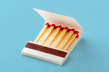 Kırmızı saçlı kibritlerle dolu kibrit kutusunu aç. Mavi arkaplanda gölgeli izole edilmiş