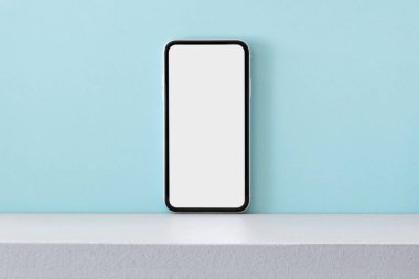 Açık mavi arkaplanda boş ekranlı modern cep telefonu