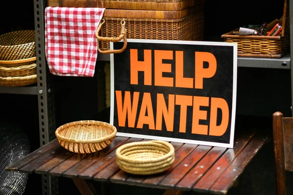 Help Wanted sign displayed in a shop selling woven baskets in a job vacancy, hiring and employment concept