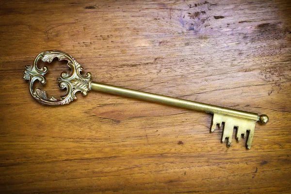 Old decorative vintage brass skeleton key on a wood background viewed high angle with copyspace and side vignette