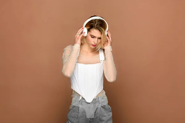 Blond Female Trendy Outfit Adjusting Headphones Listening Music Brown Background — Stock Photo, Image