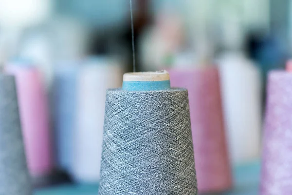 Close up detail of cashmere wool on a conical spool in a knitwear factory with lateral copyspace in a fashion manufacturing concept