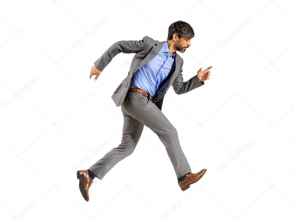 Businessman in a stylish suit walking very fast in a hurry with a determined focused expression striding out over a white background