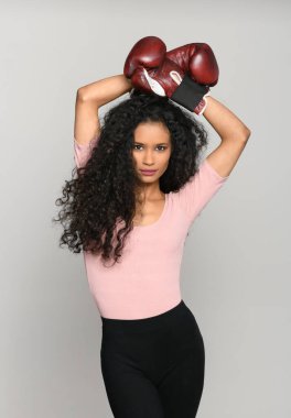 Klasik boks eldiveni giymiş, kameraya bakan ince siyah bir kadın.