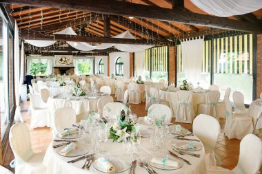 Yuvarlak masalı, sofra takımlı, çiçekli, zarif iç tasarımı düğün töreninde sunulan zarif beyaz ve mavi tonlarda.