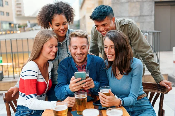 Grupo Jovens Amigos Diversos Reunidos Torno Smartphone Uma Mesa Pub — Fotografia de Stock