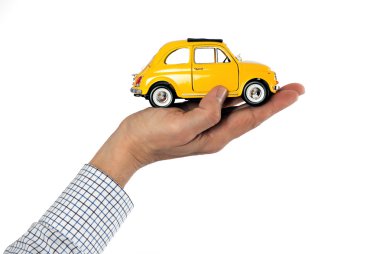 Sarı oyuncak araba tutan el