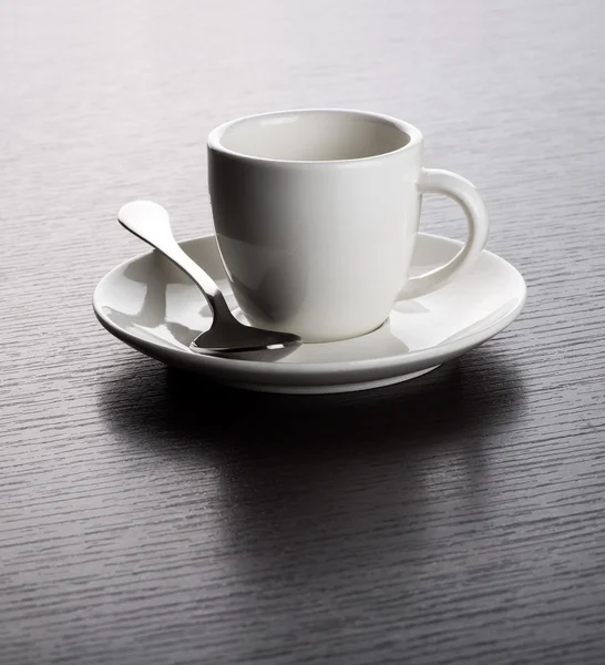 Tazza bianca vuota sul piattino con cucchiaio — Foto Stock