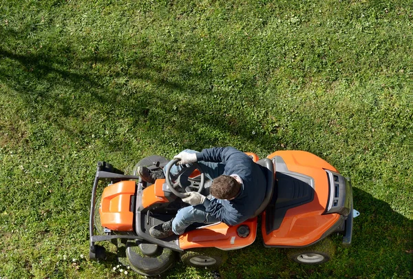 Un homme fauchant une pelouse sur une tondeuse à gazon — Photo