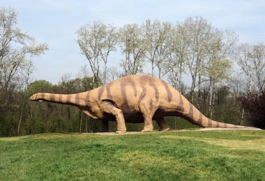 Çimenli parkında duran büyük Brontosaurus heykeli