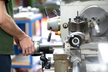 Mavi yakalı işçi el emeği bir torna ile yapıyor