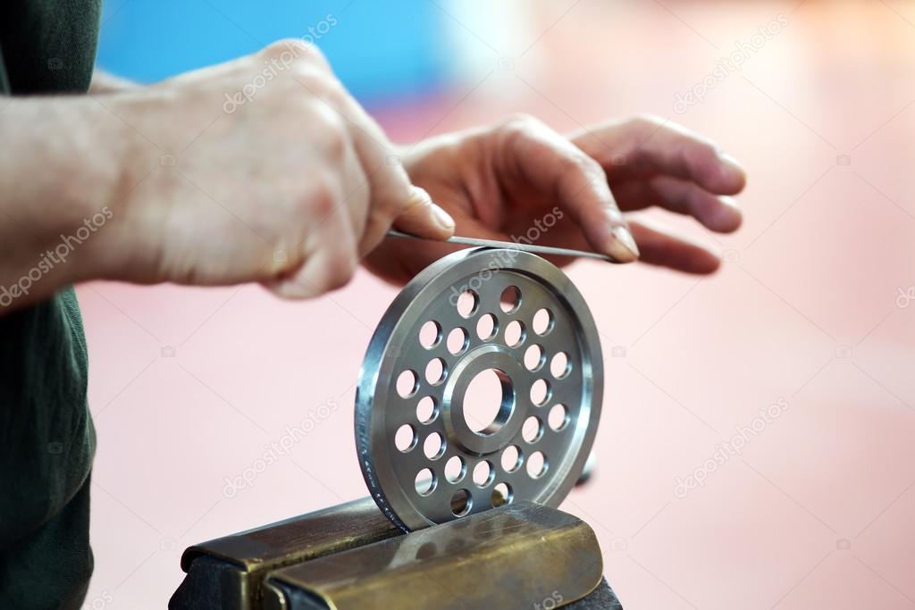 Hands smoothing with a file the edge of a wheel