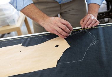 Tailor or clothing designer at work in his studio clipart