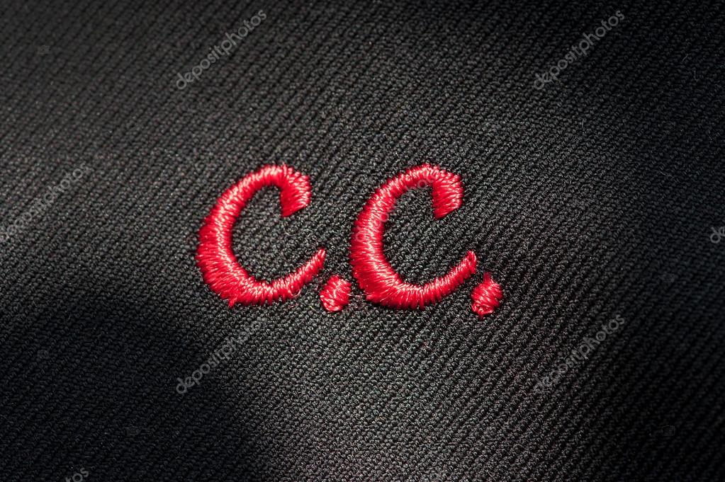 Embroidery of initials or clothing logo with C.C. in red stitching on a dark fabric in a needlework, tailor, seamstress or clothing manufacture concept