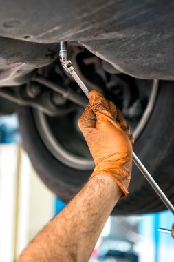 Bir İngiliz anahtarı kullanarak bir araba tamircisi