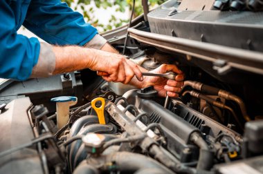 Tamircinin elleri araba motorunda bakım yapıyor, otomotiv tamiri sağlıyor.