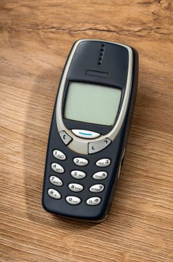 Milan, Lombardy, İtalya - 16 Ocak 2026: Iconic Nokia 3310 model, 2000 yılından kalma, ahşap bir rafta duruyor.