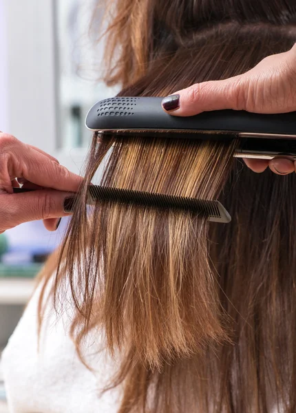 Cabeleireiro usando um alisador de cabelo — Fotografia de Stock