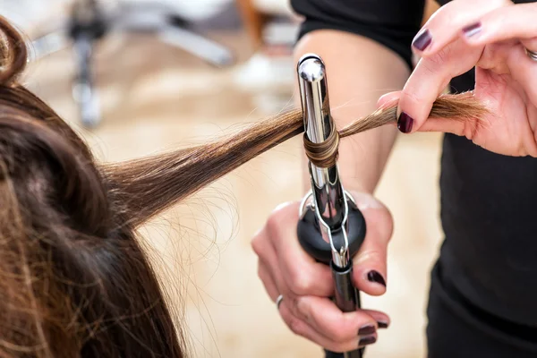 Hairstylist using a curling iron to firm ringlets — Stock Fotó