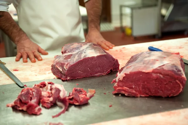Carnicero cerca de losas de carne cruda — Foto de Stock