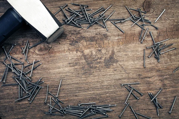 Cromo Martillo y clavos en tablero de madera — Foto de Stock