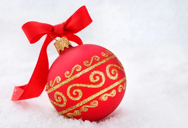 Κόκκινη Χριστουγεννιάτικη μπάλα με κορδέλα στο χιόνι — Φωτογραφία Αρχείου