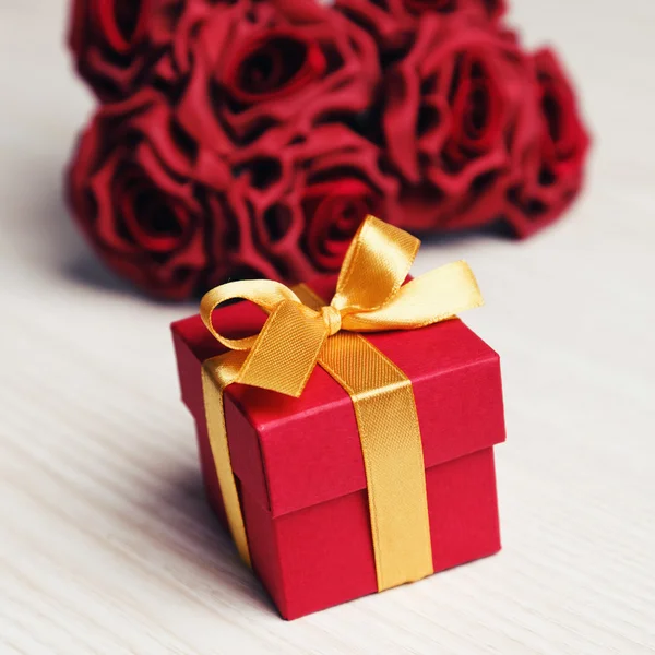 Flores rojas y caja de regalo con cinta amarilla —  Fotos de Stock