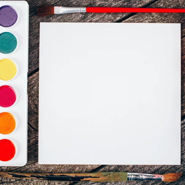 Paints for painting and brush with blank white paper sheet — Stock Photo, Image