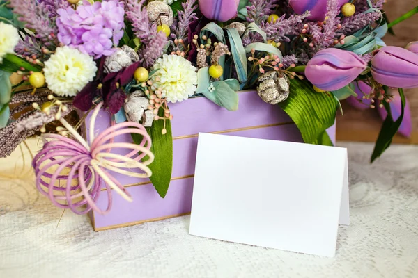 Basket decorated by flowers with a clean sheet of paper — Stock Photo, Image