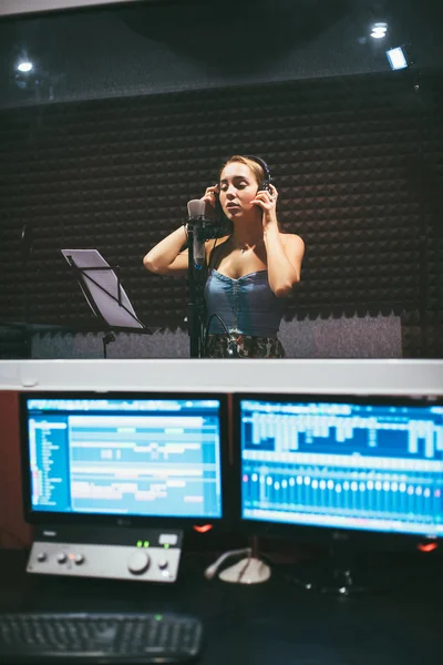 Menina vestindo fones de ouvido e cantando no microfone em estúdio de gravação — Fotografia de Stock
