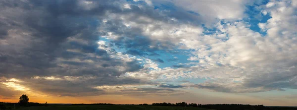 panorama beautiful cloudy sunset over green meadow, landscape