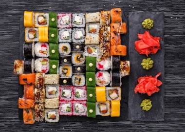 Japon mutfağı. Siyah arka planda taze malzemeli suşi. Değişik roller. Üst görünüm.