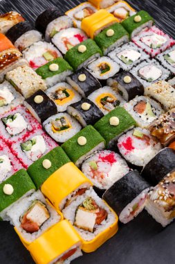 Suşi seti. Farklı türde Maki ve Nigiri suşisi. Restoranda parlak ve renkli bir tören. Koyu taş suşi tahtalarında servis edilmiş. Kocaman bir suşi seti..