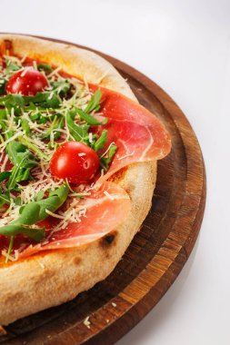 Tahta tezgahta sıcak pizzanın en üst görüntüsü. Prosciutto, domates, Hollanda peyniri.